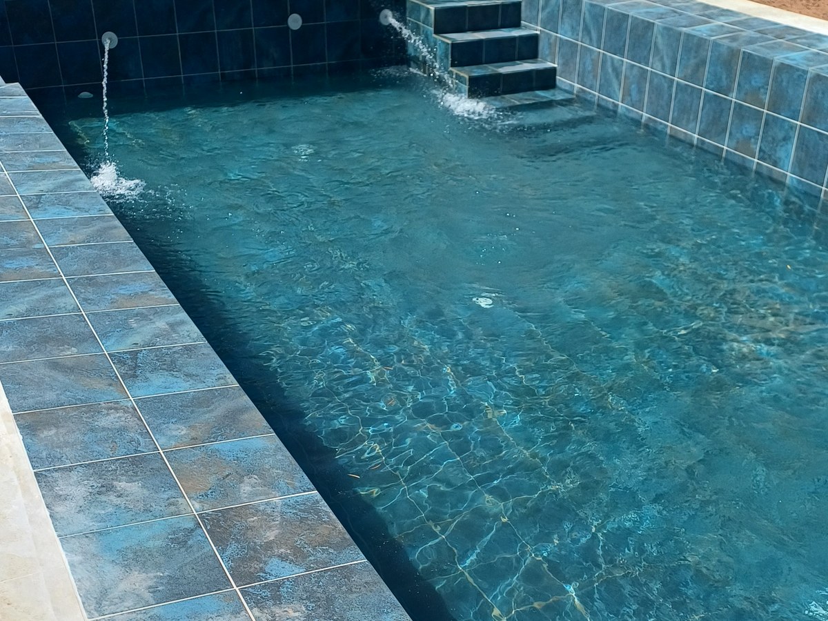 Piscine terminée en eau, jets et escalier carrelés